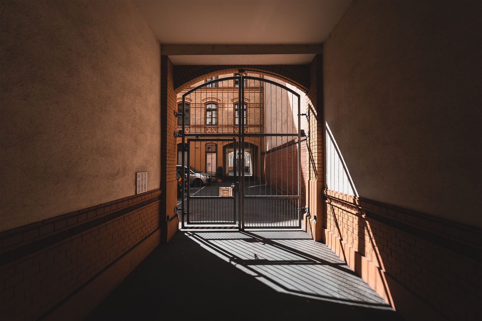 Fotografía de referencia de un acceso con portón metálico y sombras de luz natural; no es un trabajo del taller